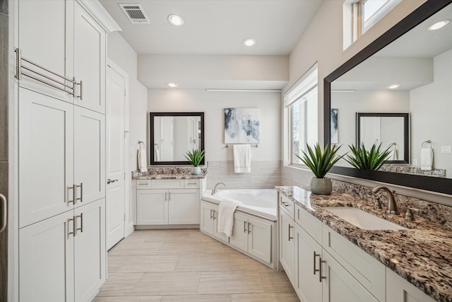 bathroom with a bath, recessed lighting, visible vents, and a sink