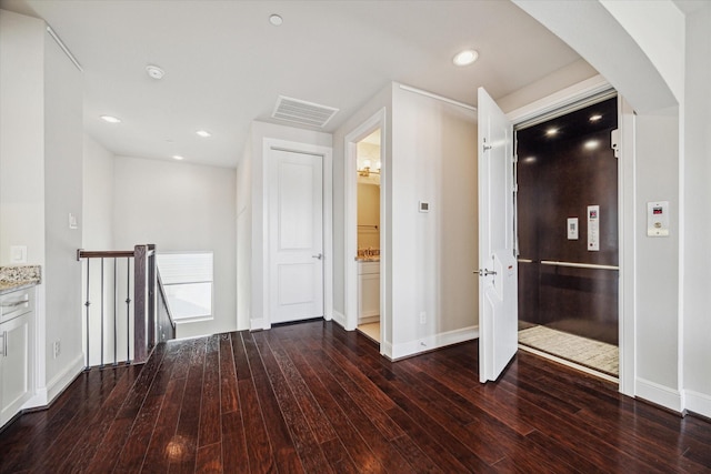 hall with visible vents, hardwood / wood-style floors, an upstairs landing, recessed lighting, and arched walkways