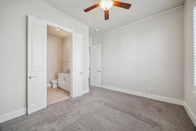 unfurnished bedroom with light carpet, ceiling fan, ensuite bath, and baseboards