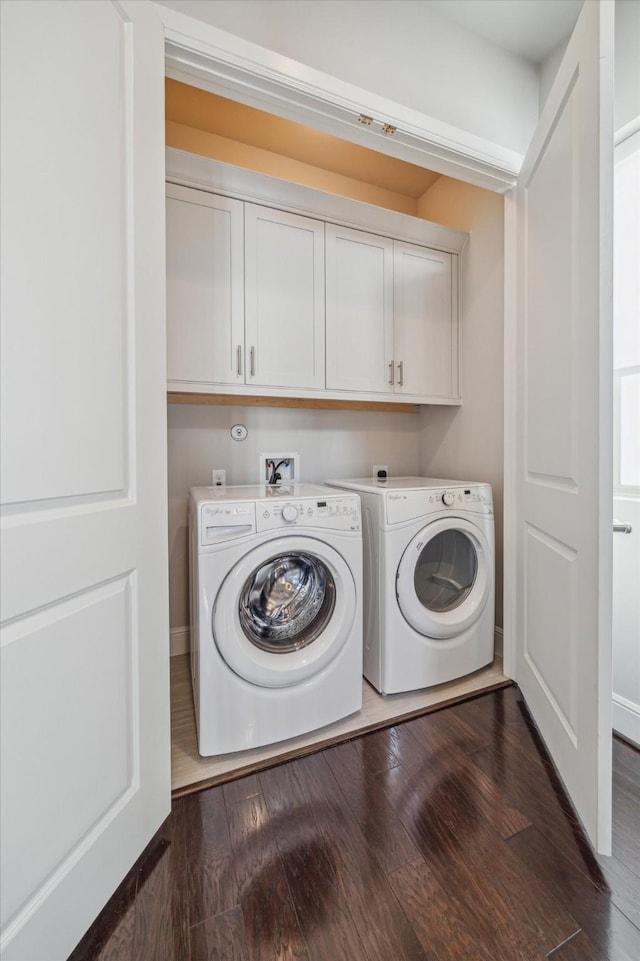 washroom with cabinet space, washer and dryer, dark wood-type flooring, and baseboards