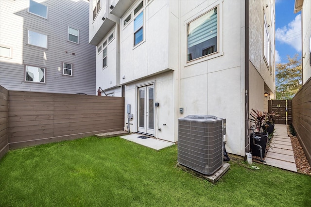 back of property with central air condition unit, a yard, a fenced backyard, and stucco siding