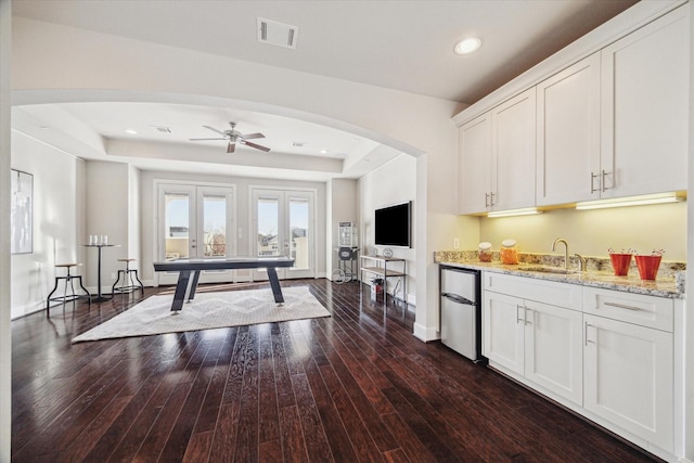 interior space with baseboards, visible vents, dark wood finished floors, a tray ceiling, and recessed lighting