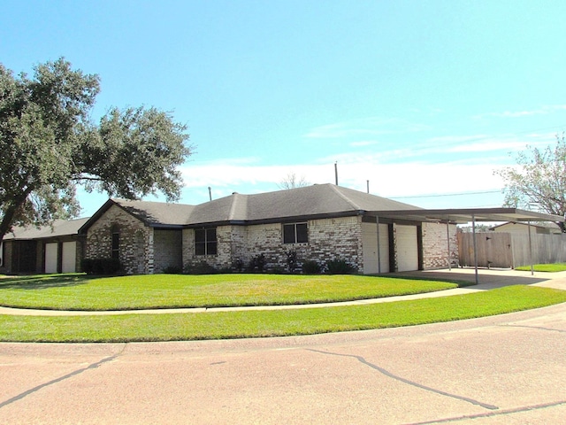 view of front facade featuring a front yard, concrete driveway, a carport, a garage, and brick siding