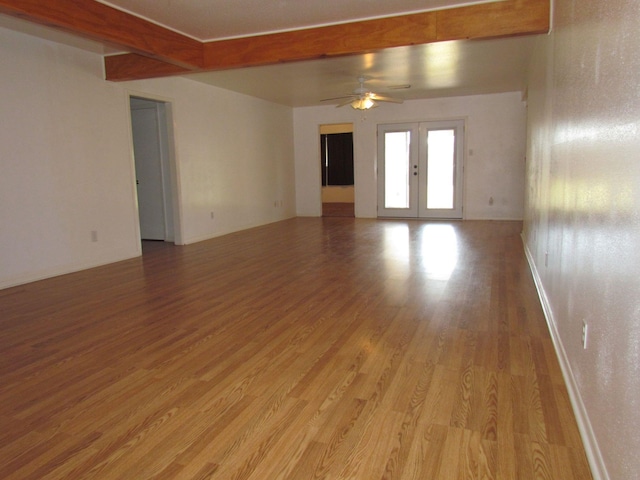 unfurnished room with french doors, light wood-style floors, beamed ceiling, and ceiling fan