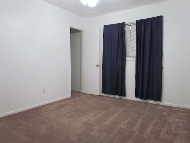 carpeted empty room with baseboards and a ceiling fan