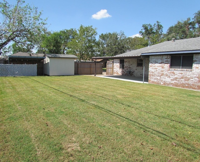 view of yard with an outbuilding, a shed, a patio area, and fence