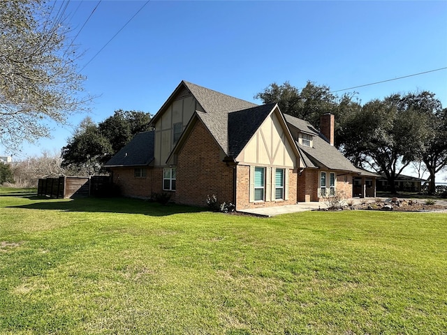 view of home's exterior with brick siding, a chimney, a shingled roof, and a yard