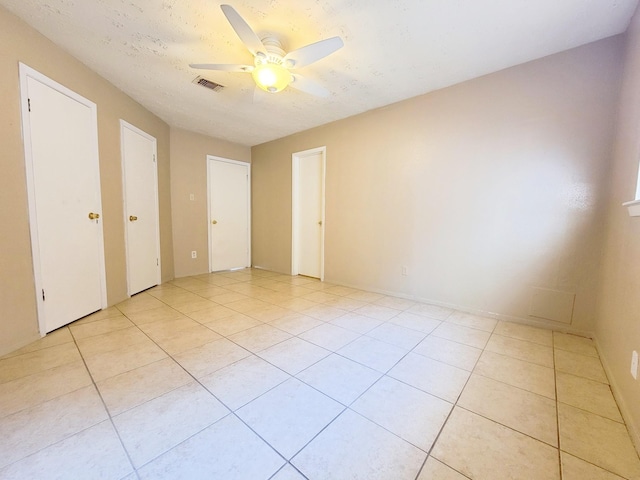 unfurnished bedroom featuring ceiling fan, visible vents, a textured ceiling, and light tile patterned flooring