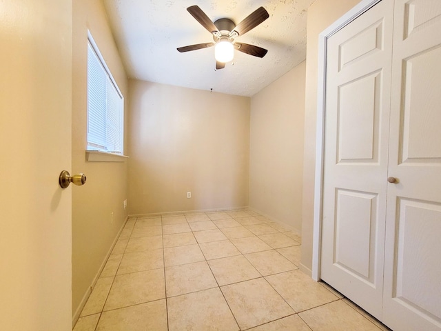 spare room featuring light tile patterned floors, baseboards, and a ceiling fan