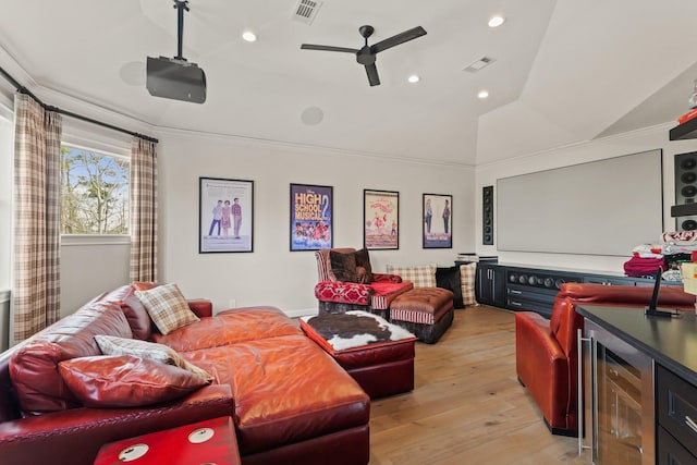 home theater featuring visible vents, crown molding, a bar, and light wood-type flooring