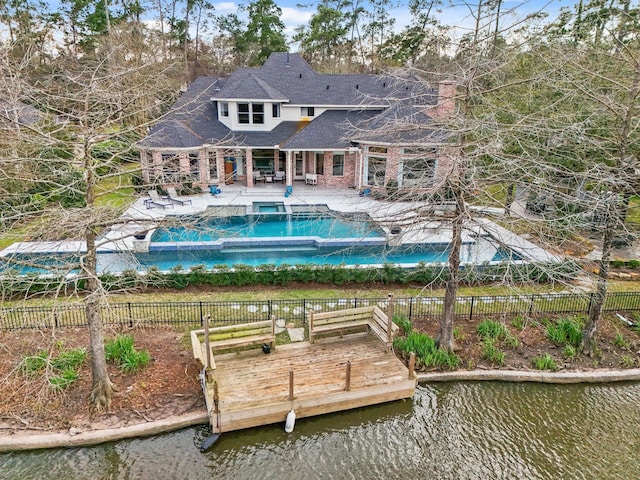 rear view of property featuring a patio, a fenced backyard, a deck with water view, and a pool with connected hot tub