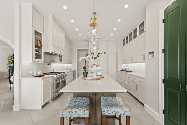 kitchen with light tile patterned flooring, white cabinets, and double oven range