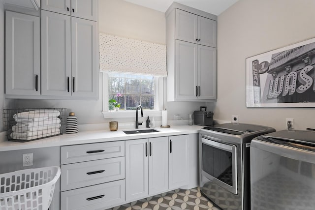 clothes washing area featuring washing machine and clothes dryer, cabinet space, light floors, and a sink