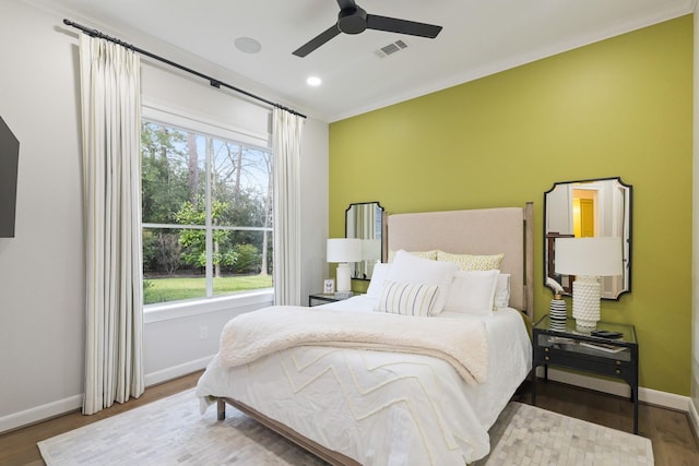 bedroom featuring visible vents, crown molding, baseboards, and wood finished floors