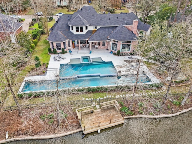 rear view of house featuring a patio, a pool with connected hot tub, and roof with shingles