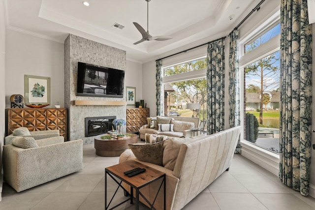 living room featuring light tile patterned floors, a tray ceiling, visible vents, and a fireplace