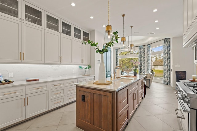 kitchen featuring tasteful backsplash, range with two ovens, light tile patterned floors, recessed lighting, and a sink