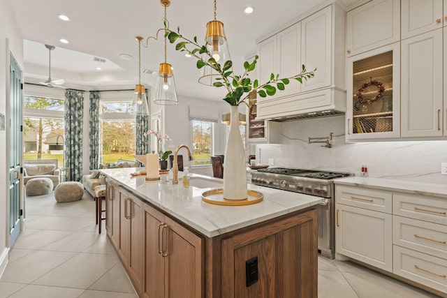 kitchen featuring light stone counters, recessed lighting, a sink, high end stove, and backsplash