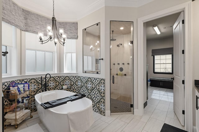 bathroom with a notable chandelier, a freestanding bath, a shower stall, and crown molding