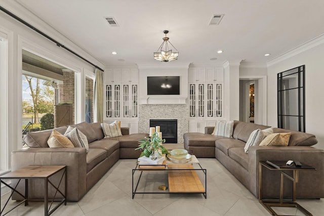 living area with light tile patterned flooring, visible vents, crown molding, and a glass covered fireplace