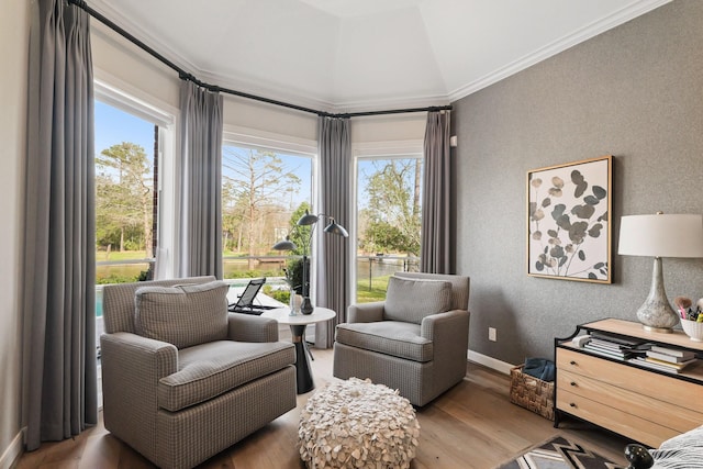 living area with lofted ceiling, plenty of natural light, wood finished floors, and ornamental molding