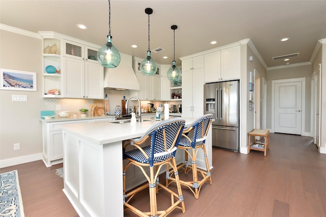 kitchen featuring custom exhaust hood, high end refrigerator, a sink, and open shelves