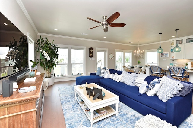 living room with visible vents, ornamental molding, recessed lighting, ceiling fan with notable chandelier, and wood finished floors