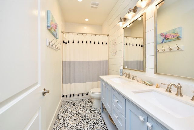 full bathroom featuring a sink, toilet, double vanity, and tile patterned floors