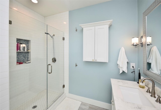 bathroom featuring a shower stall, vanity, and baseboards