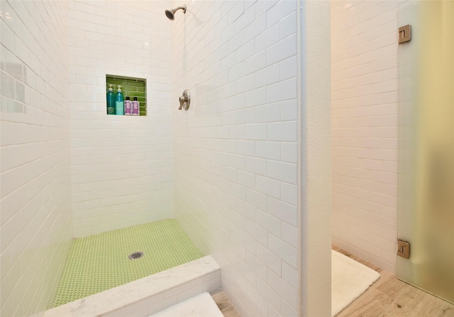 full bath with a tile shower and wood finished floors