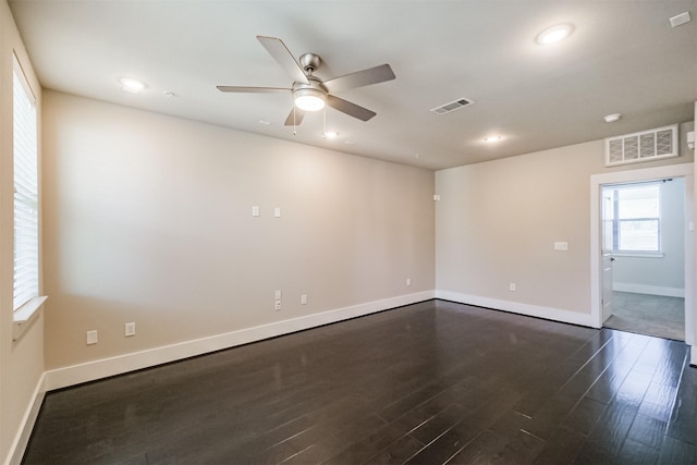 empty room with dark wood finished floors, visible vents, and recessed lighting