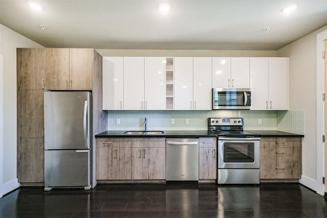 kitchen featuring dark countertops, tasteful backsplash, appliances with stainless steel finishes, and a sink