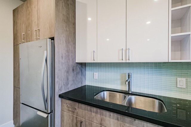 kitchen featuring freestanding refrigerator, a sink, decorative backsplash, white cabinetry, and modern cabinets