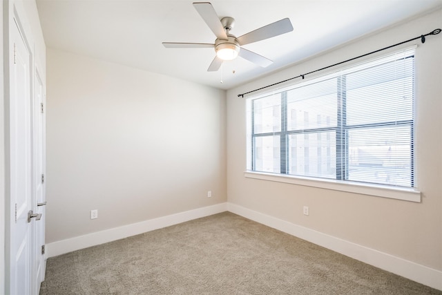 carpeted spare room with a ceiling fan and baseboards