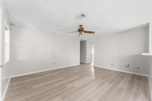 empty room featuring visible vents, a textured ceiling, light wood finished floors, baseboards, and ceiling fan