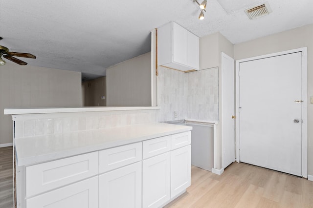 kitchen with visible vents, light wood-style floors, light countertops, and white cabinetry