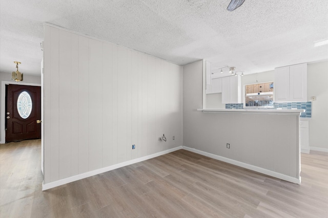 unfurnished living room with plenty of natural light, a textured ceiling, and light wood-type flooring