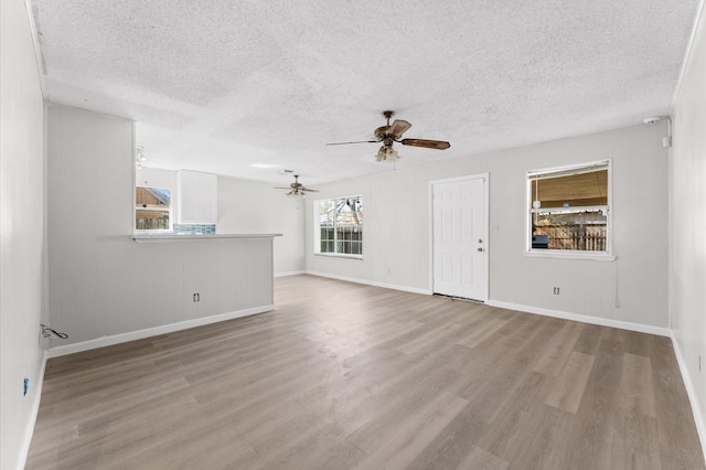 unfurnished living room featuring a textured ceiling, a ceiling fan, and wood finished floors