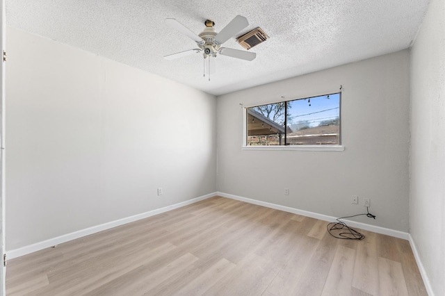 empty room featuring wood finished floors, visible vents, baseboards, ceiling fan, and a textured ceiling