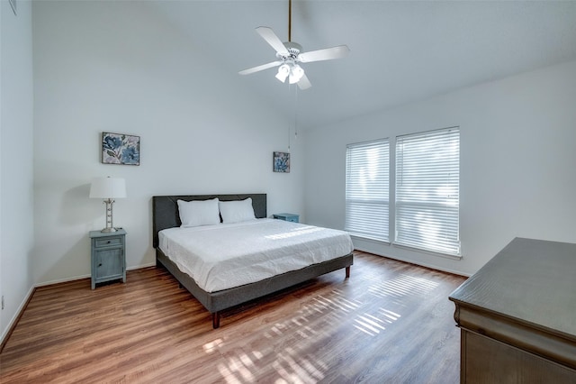 bedroom with ceiling fan, high vaulted ceiling, baseboards, and wood finished floors