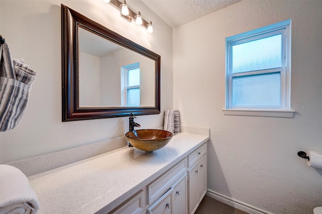 bathroom featuring a wealth of natural light, a textured ceiling, vanity, and a textured wall