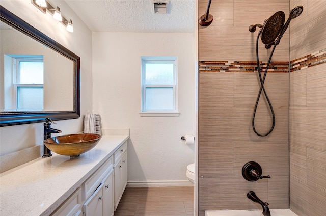 bathroom with visible vents, toilet, a textured ceiling, baseboards, and vanity