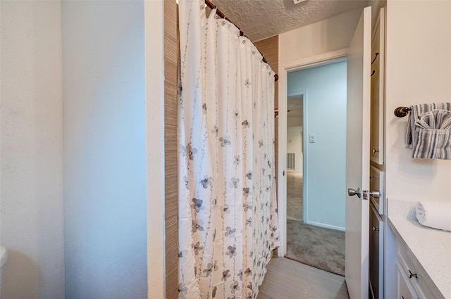 bathroom with vanity, a shower with curtain, visible vents, and a textured ceiling