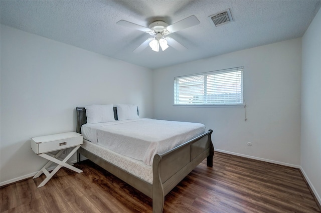 bedroom with visible vents, baseboards, a textured ceiling, and wood finished floors