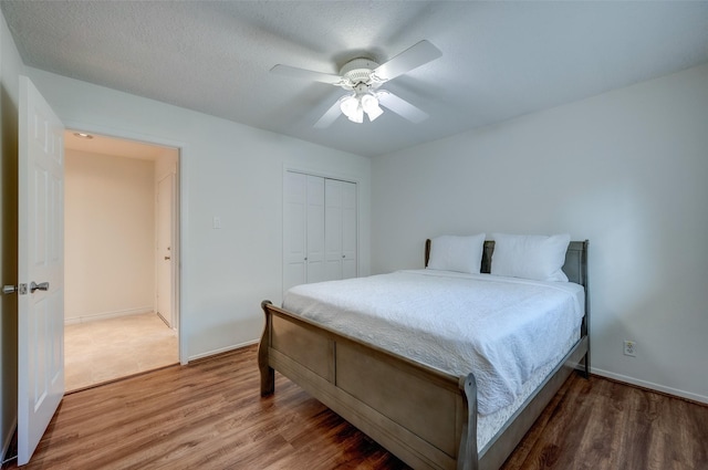 bedroom featuring a closet, baseboards, wood finished floors, and a ceiling fan