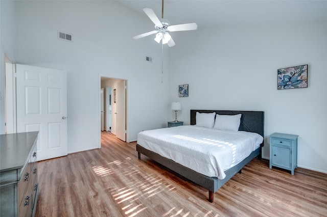 bedroom featuring a ceiling fan, visible vents, light wood finished floors, and high vaulted ceiling