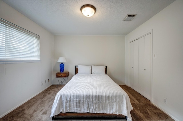 carpeted bedroom featuring visible vents, a textured ceiling, and a closet