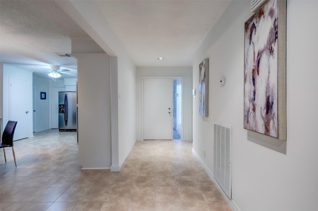 hall featuring visible vents, baseboards, and a textured ceiling