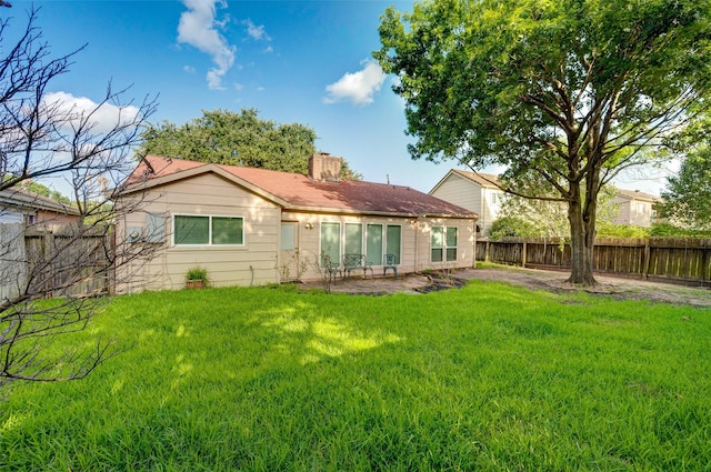 back of property featuring a patio area, a lawn, a chimney, and fence