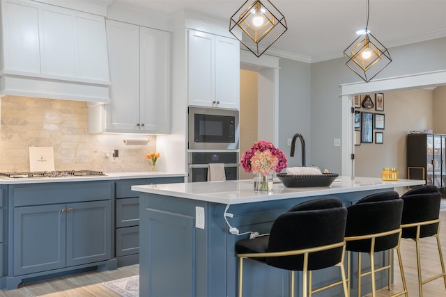 kitchen featuring backsplash, light countertops, ornamental molding, light wood-style floors, and stainless steel appliances